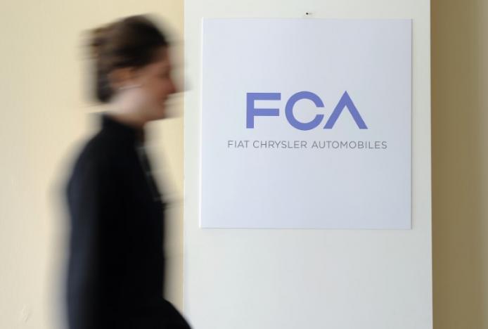 A woman walks past a logo of Fiat Chrysler Automobiles (FCA) in Turin March 31, 2014. REUTERS/Giorgio Perottino